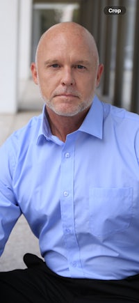 a bald man in a blue shirt and black pants